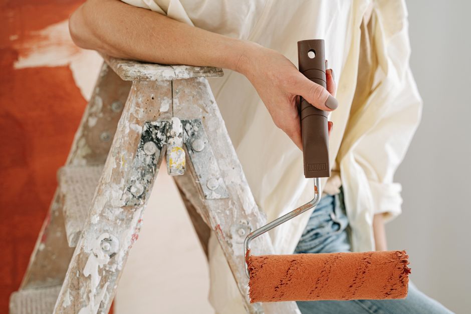 Professional painter working with roller on interior wall during renovation